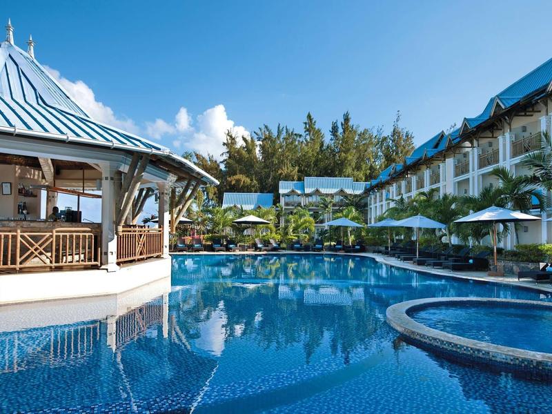 Hotel con piscina blu, padiglione e edifici bianchi sotto un cielo azzurro.