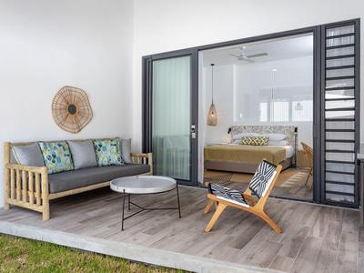 Moderner Hotelbalkon mit gemütlicher Holz-Lounge, Kissen und Blick ins Schlafzimmer.