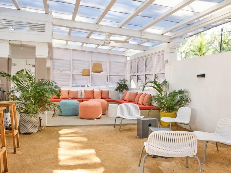 Jasna, nowoczesna przestrzeń wypoczynkowa z kolorowymi poduszkami, roślinami i szklanym dachem w hotelu.