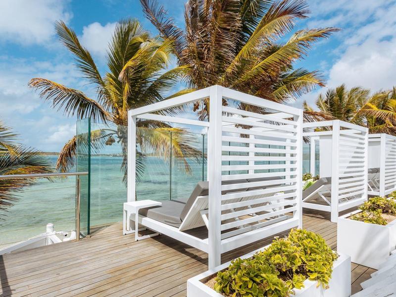 Nowoczesne białe łóżka lounge na tarasie z widokiem na morze i palmami w tle
