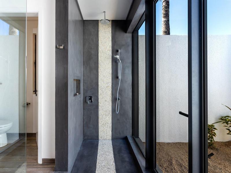 Nowoczesny prysznic ze szklaną ścianą i dostępem do małego zewnętrznego obszaru z roślinami.