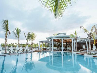 Moderne zwembadomgeving met palmbomen en poolbar in een tropisch resort.