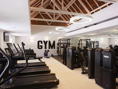 Moderner Fitnessraum mit Laufbändern, Kraftgeräten und hellem Interieur.