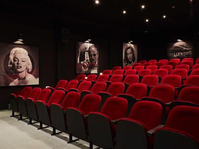 Kleines Heimkino mit roten Sitzen und Filmplakaten an den Wänden