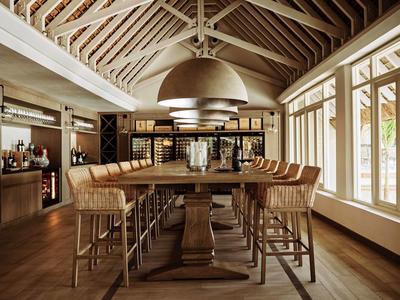 Moderne eetzaal met houten tafels, stoelen en grote ramen in een hotel.