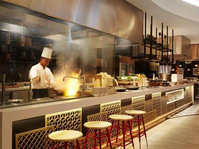 Kok die in open keuken van restaurant kookt met moderne inrichting en bar.