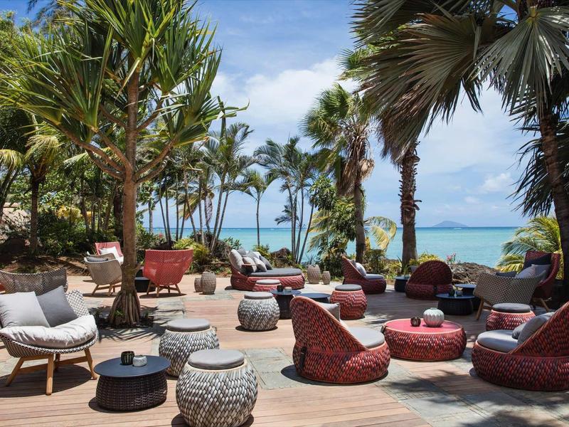 Buitenzitgedeelte met moderne meubels onder palmbomen aan zee