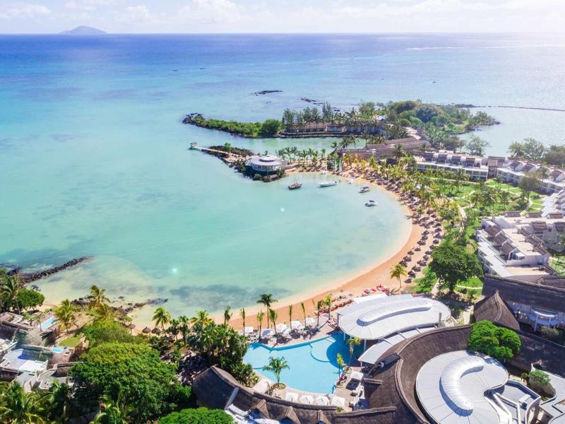 Luchtfoto van een tropisch resort met stranden, zwembaden en turquoise zee.