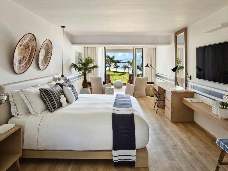 Modern hotelkamer met groot bed, balkon en uitzicht op palmbomen en zee