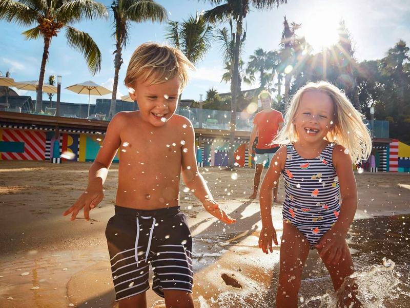 Twee kinderen spelen blij met water buiten bij zonnig weer.