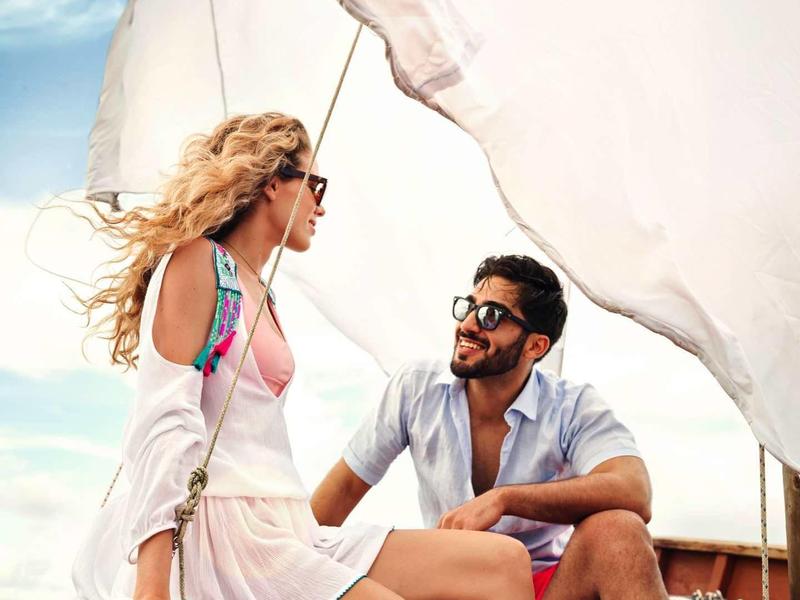 Een stel ontspant op een zeilboot bij zonnig weer.