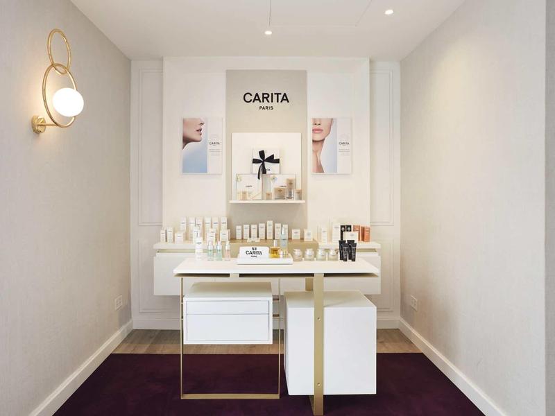 Eenvoudige spa-weergave met witte producten op een goud-witte tafel tegen een minimalistische muur.