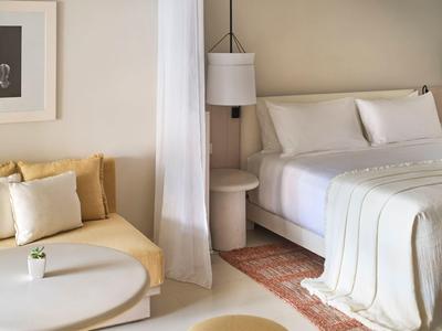 Helles Hotelzimmer mit großem Bett, gemütlicher Sitzecke und modernem Dekor.