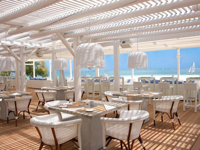 Moderní otevřená odpočinková zóna s růžovým barem, židlemi a mnoha zelenými rostlinami.