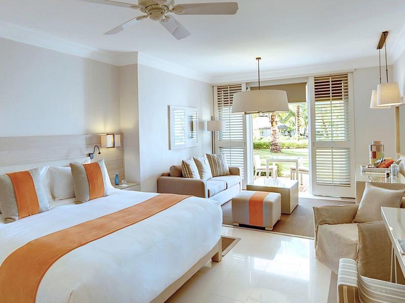 Moderní hotelový pokoj s velkou postelí, pohovkou, psacím stolem a výhledem na terasu.