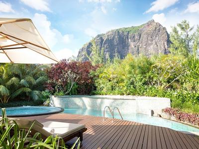 Zwembad met parasol en ligstoel voor bergachtig landschap onder blauwe lucht