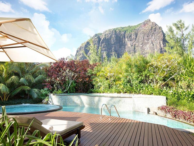 Zwembad met parasol en ligstoel voor bergachtig landschap onder blauwe lucht