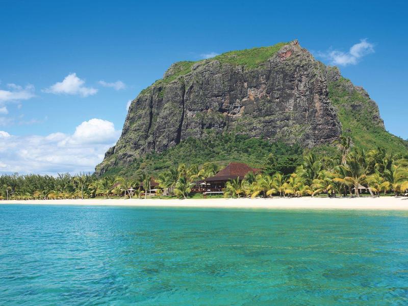 Berg boven tropisch zandstrand met helderblauwe zee en blauwe lucht.