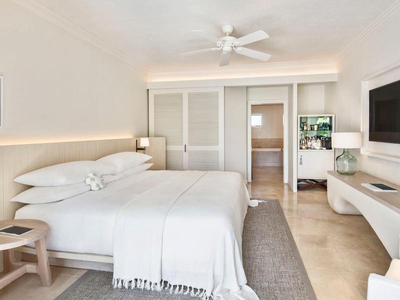 Licht ingericht hotelkamer met groot tweepersoonsbed en moderne flatscreen-tv.