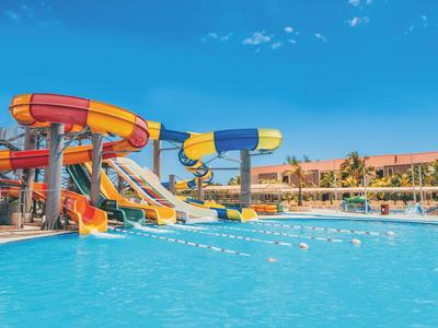 Wasserpark mit bunten Wasserrutschen und klarem Pool bei sonnigem Wetter.