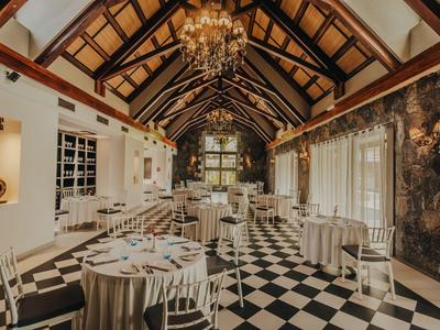 Eleganter Speisesaal mit hohen Holzbalkendecken und schwarz-weiß kariertem Boden.