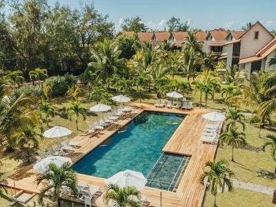 Langer Swimmingpool in tropischem Resort mit Palmen und Sonnenschirmen.