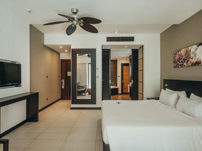 Modernes Hotelzimmer mit Doppelbett, Deckenventilator, Wand-TV und großem Spiegel.