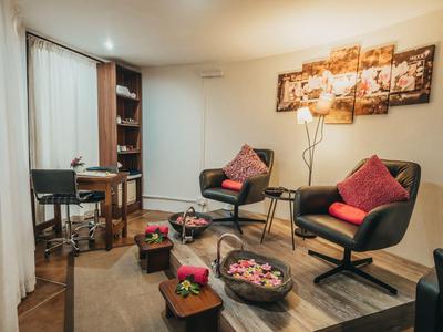 Gemütlicher Sitzbereich mit Sesseln, Couchtisch und Wandkunst in einem warm beleuchteten Raum.