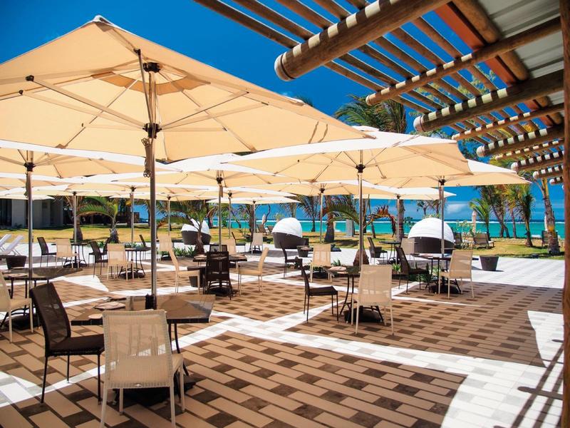 Buiten zitgedeelte met parasols en stoelen bij een zwembad onder een heldere blauwe lucht.