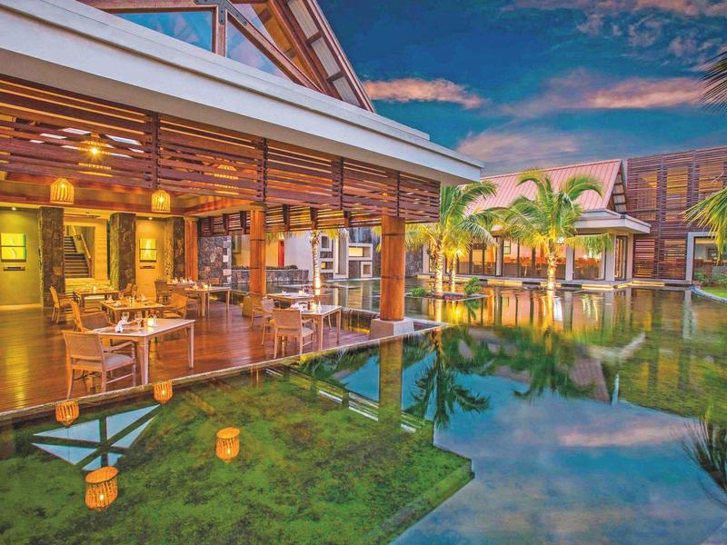 Luxe hotelterras met buiten dineren bij een rustige pool bij zonsondergang.