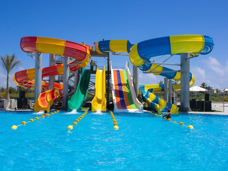 Felle glijbanen en zwembad bij een zonnig waterpark met heldere blauwe lucht.