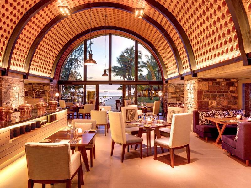 Hell beleuchteter Restaurantraum mit gewölbter Decke, Holzmöbeln und großen Fenstern zum Garten.