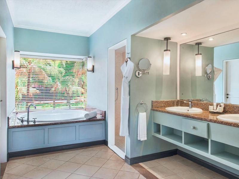 Helles Badezimmer mit großer Badewanne, Doppelwaschbecken, blauen Wänden und großen Fenstern.