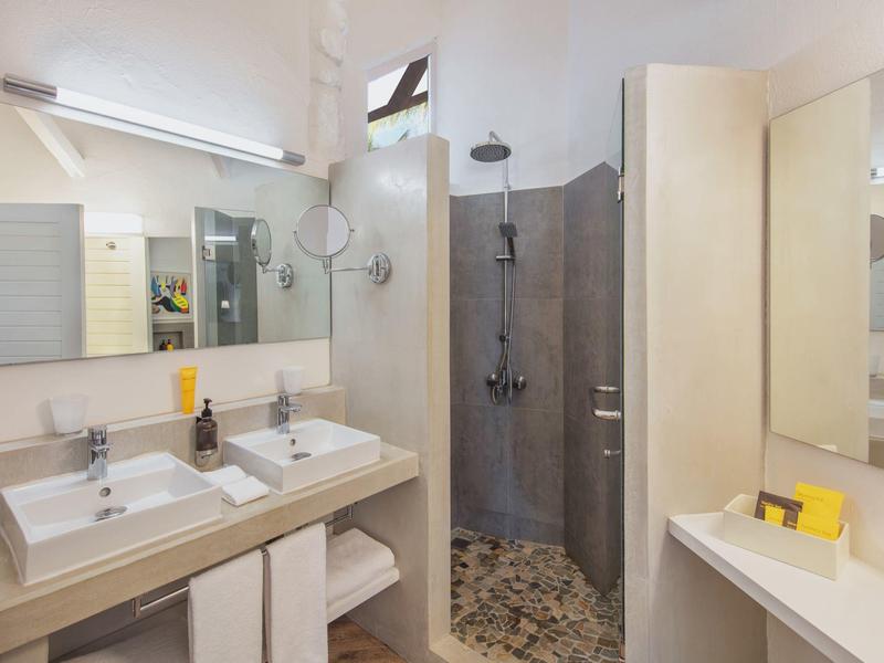 Moderne badkamer met dubbele wastafels, inloopdouche, grote spiegel en handdoekopslag.