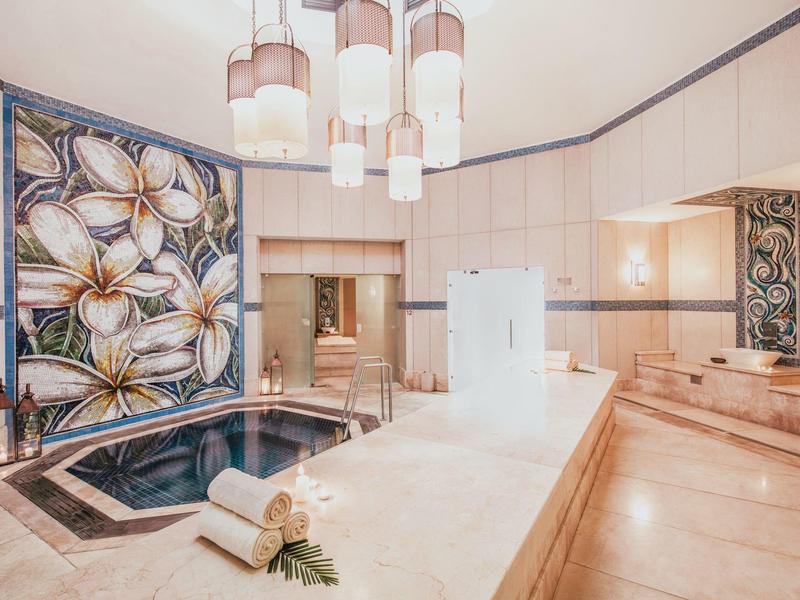 Luxe spa-ruimte met binnenjacuzzi en bloemrijke wanddecoratie.