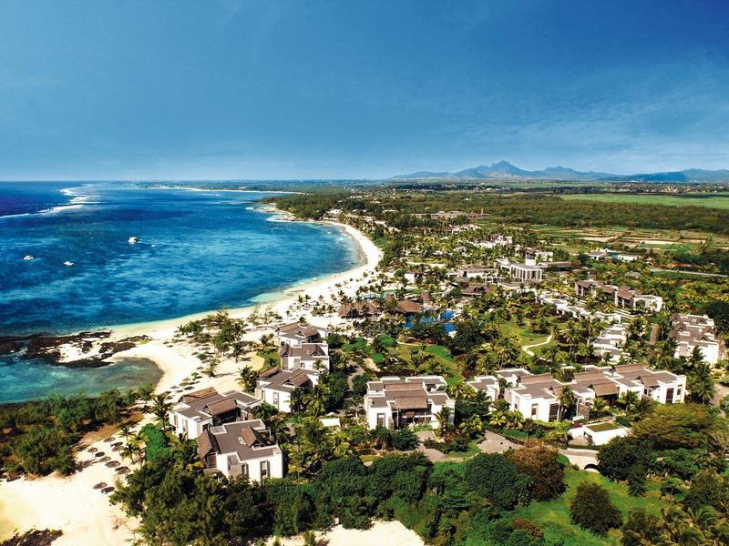 Kustresort met witte zandstranden, turquoise water en verspreide hotels omgeven door groen.