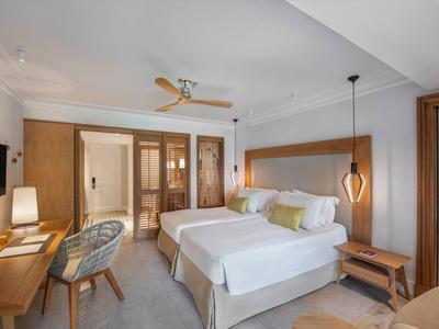 Habitación de hotel moderna con dos camas, muebles de madera y iluminación elegante.