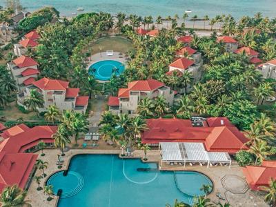 Luxuriöse Resortanlage mit großen Pools, roten Dächern, vielen Palmen und Meer im Hintergrund.