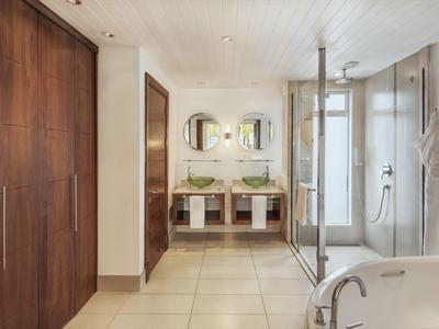 Modernes Hotelbadezimmer mit Doppelwaschbecken, Glasdusche und Holzschränken.