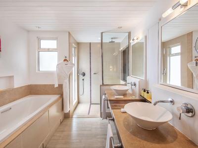 Modernes Badezimmer mit Badewanne, Glasdusche, Waschtisch und großem Spiegel in neutralen Tönen.