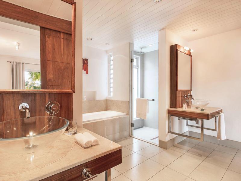 Helles Badezimmer mit zwei Waschtischen, Badewanne, Holzdetails und modernen Armaturen.