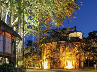 Illuminated hotel building with stone details surrounded by trees at dusk.