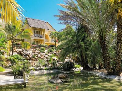 House with tropical plants and pond in sunny vacation setting