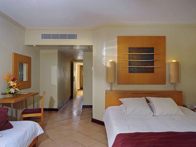 Hotelzimmer mit Doppelbett, Sofa, Schreibtisch und warmen Farbnuancen.