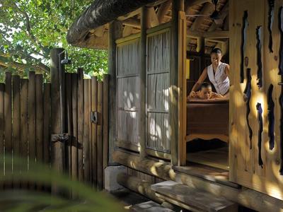 Man in white shirt sits on bed in rustic wooden cabin with garden