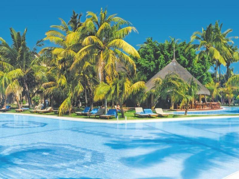 Large pool with blue water and palm trees under clear sky in tropical hotel resort
