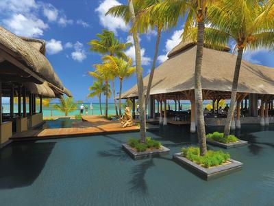 Luxusní resort s palmami, vodními prvky a výhledem na modré moře pod jasnou oblohou.