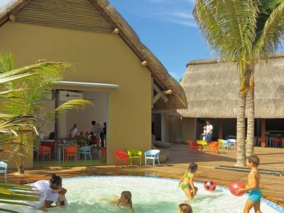 Děti si hrají v malém bazénu vedle tropického domu s palmovou zahradou.