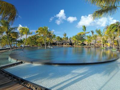 Großer Pool mit Palmen und Sonnenschein in tropischem Resort