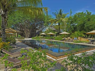 Poklidná venkovní bazénová plocha s lehátky a slunečníky v tropickém prostředí.